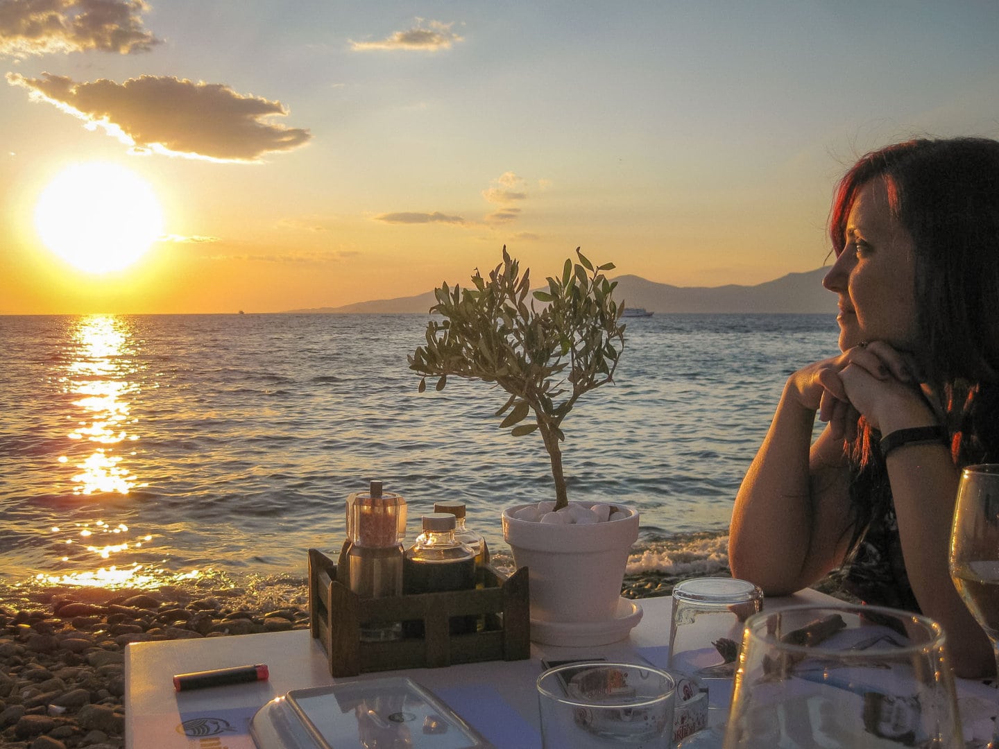 Woman at dinner table in Little Venice, Mykonos during sunset.