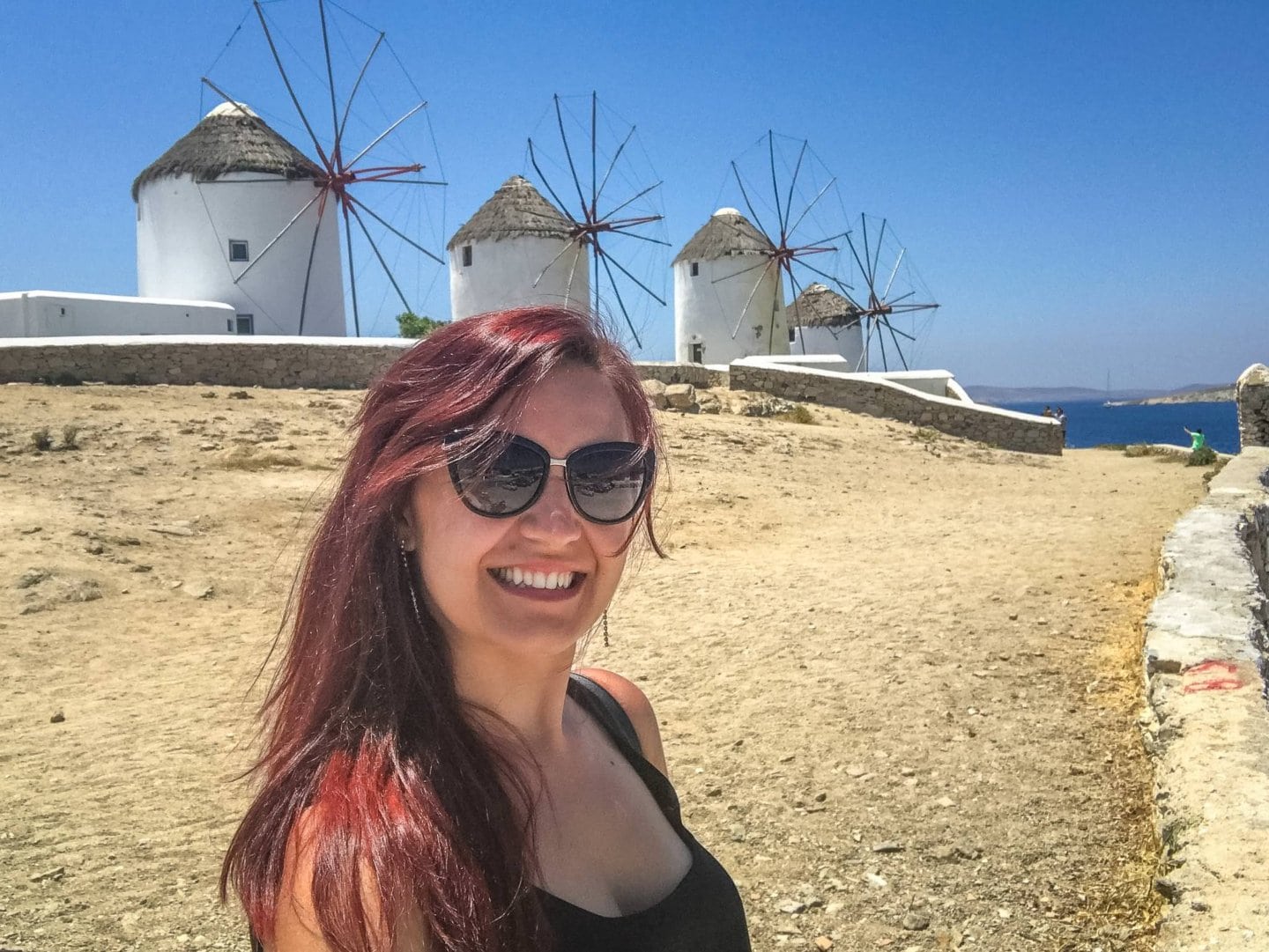 Woman in front of the iconic Mykonos windmills in Little Venice.