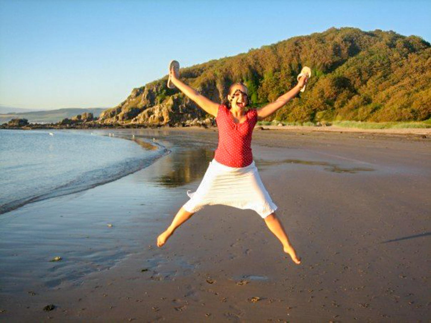 Girl jumping for joy on a beach in Maybole, Scotland.