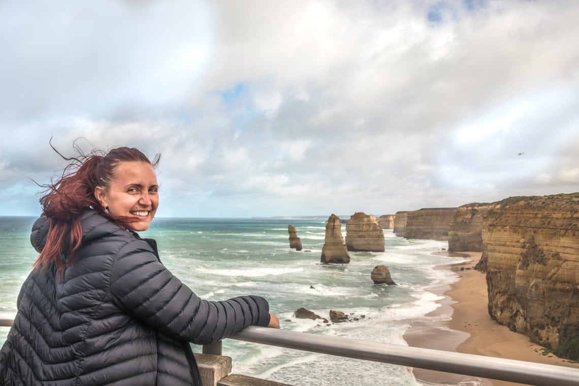 girl leaning on rail looking over the 12 apostles rock formations on Great Ocean Road