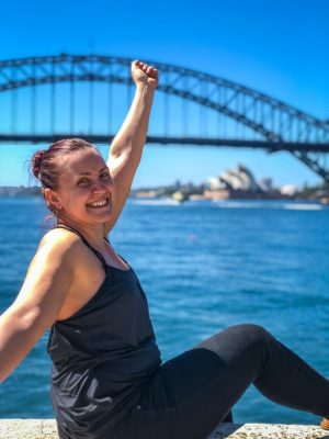 girl sitting on a ledge overlooking Sydney Harbour Bay and Sydney Opera House