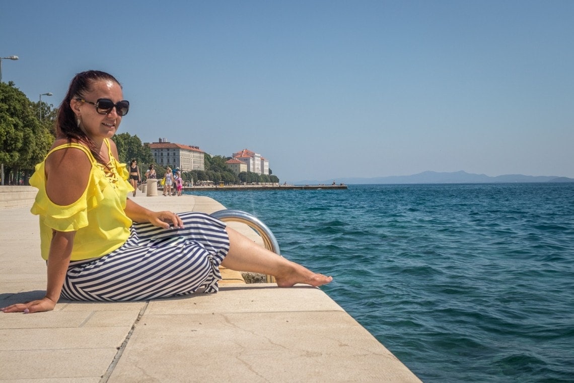 girl sitting on pavement by the waterfront in Zadar
