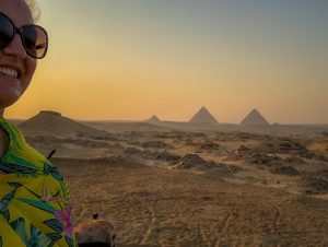 girl on a camel at sunset with the pyramids in the background