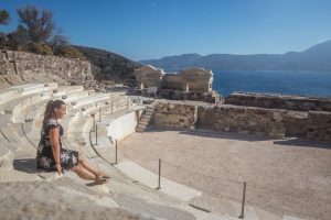 girl sitting in a theatre with a view of the Aegean sea