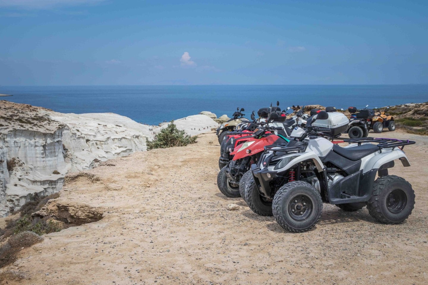 a row of quad bikes lined up at the entrance of a beach