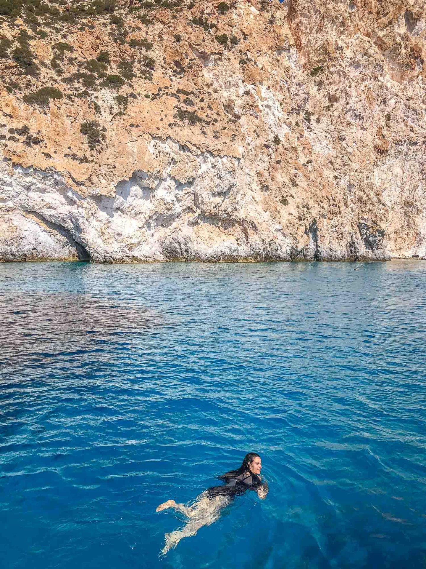 a girl swimming in crystal blue waters of Polyegos beach near Milos