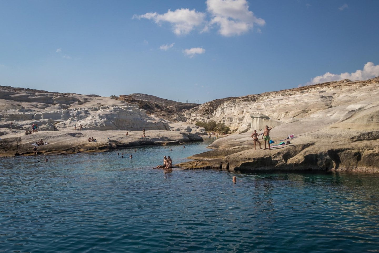 sunbathers on Milos island seen in passing from a sailing boat