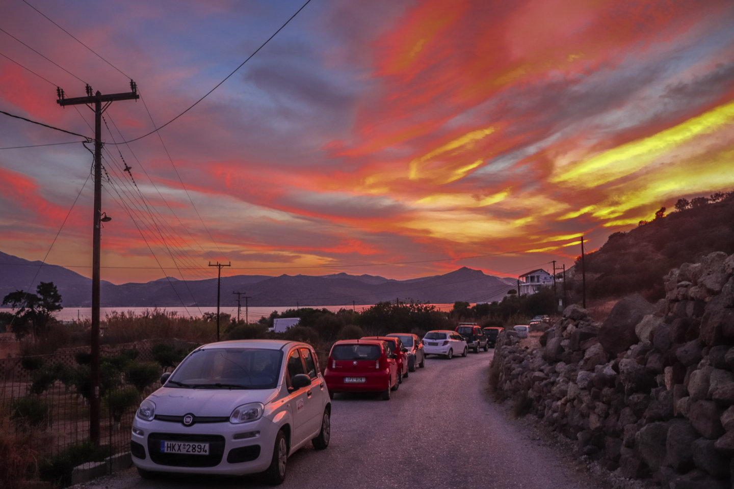 cars on a street near a Greek village during sunset