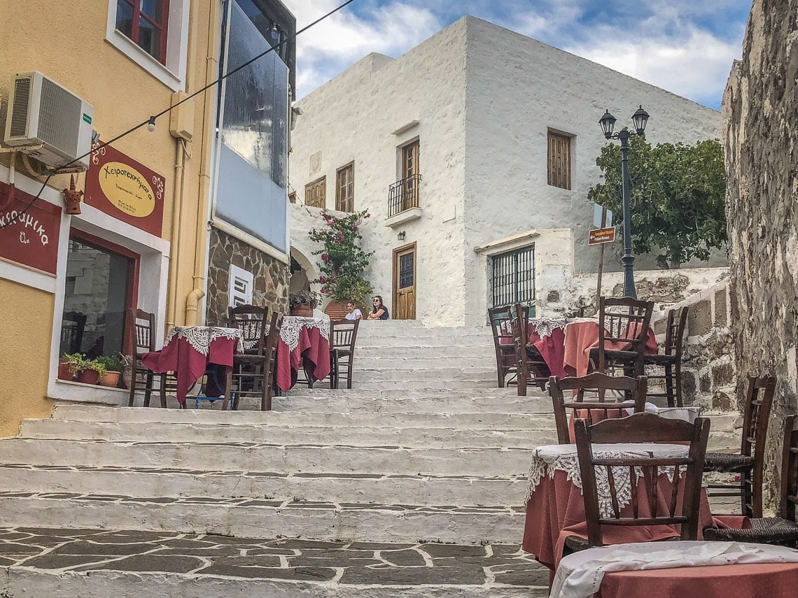 view of restaurant tables on cobblestone steps in Plaka, Milos.