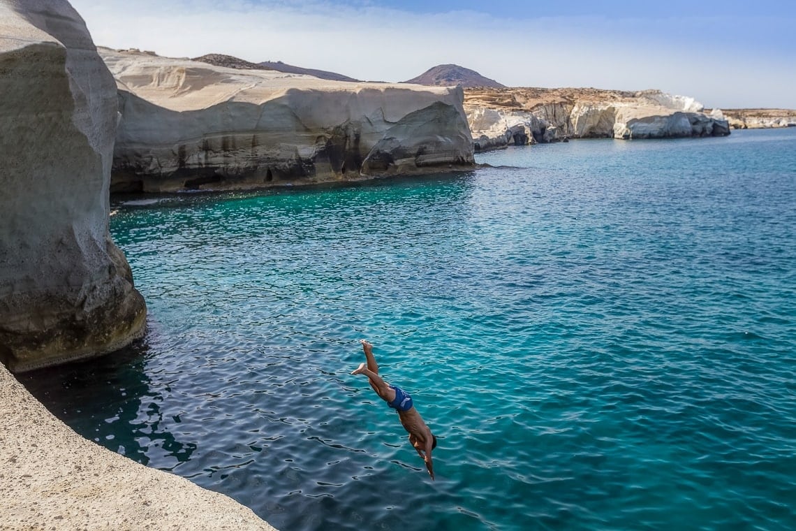 man diving off a cliff in Milos