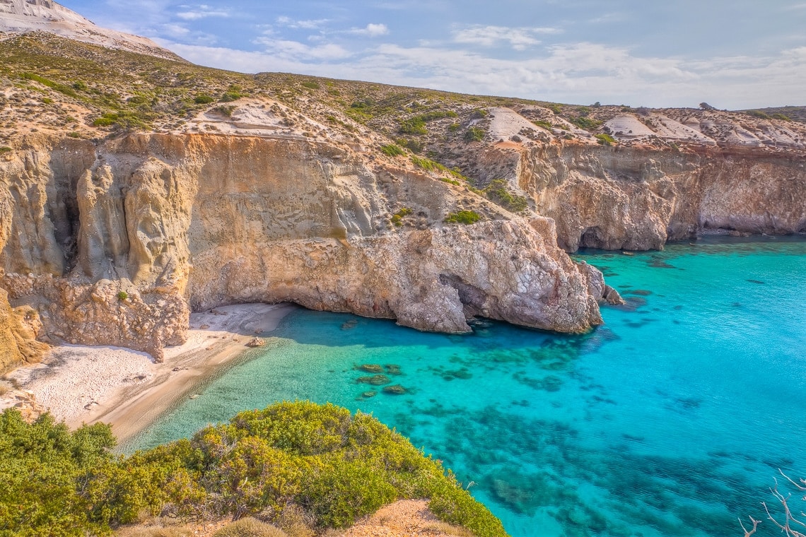a secluded beach in Milos seen from the top of a cliff