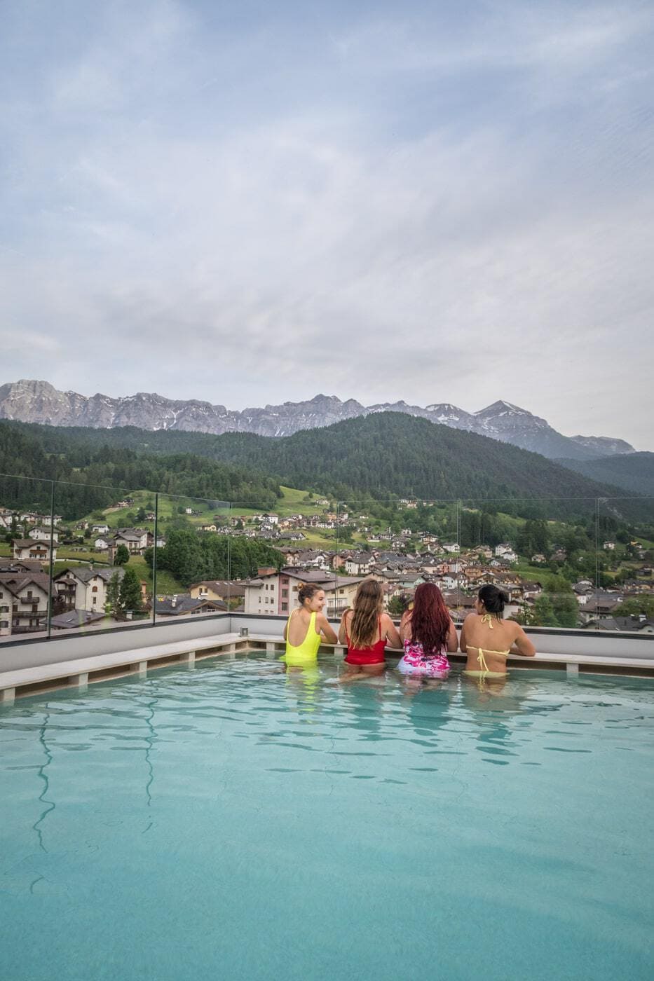 four women in a rooftop pool enjoying a panoramic view of the dolomites