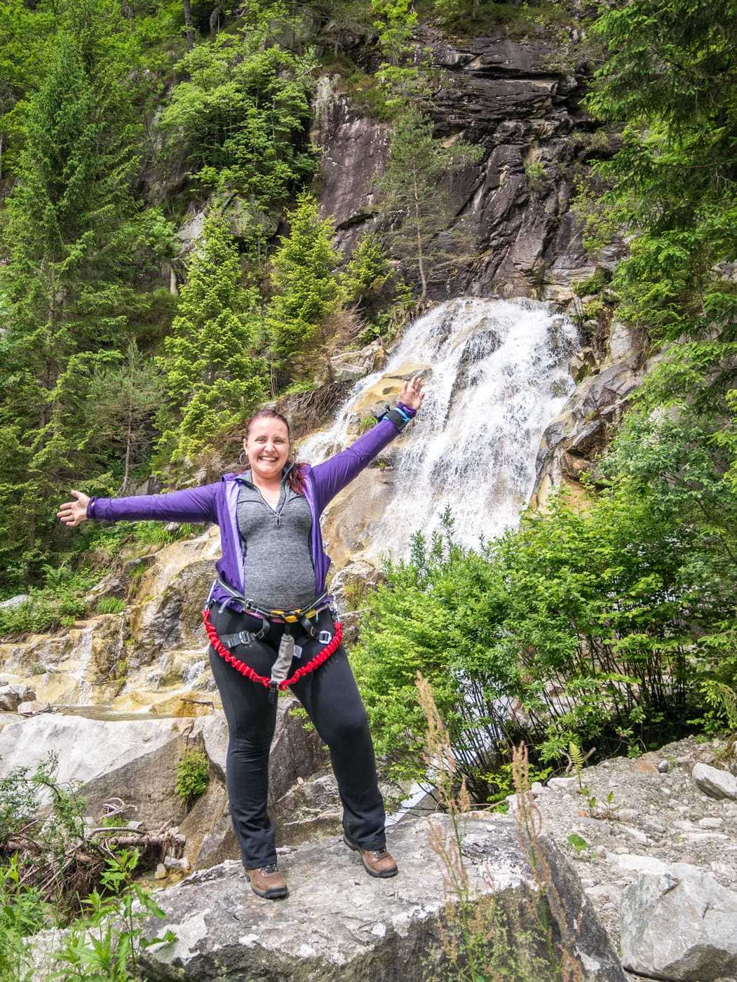 woman standing in front of a waterfall near via ferrata val di scala in valle del vanoi