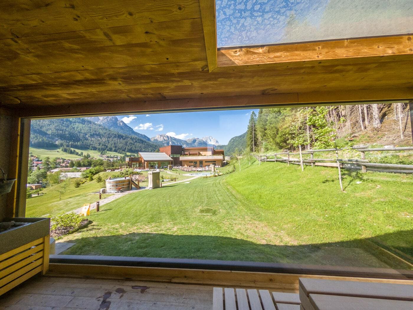 view from inside a sauna room on the lawn of a spa in val di fassa