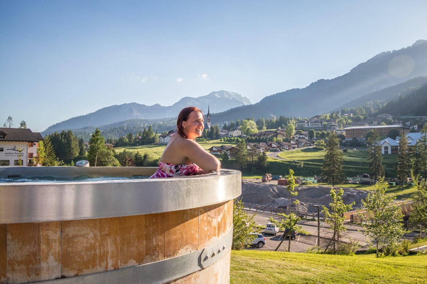woman admiring the Dolomite mountains from an outdoor hot tub  in the trentino region