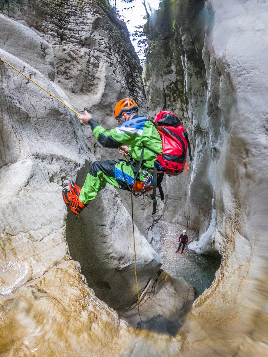 a guide hanging off a ledge while canyoning in val noana trentino