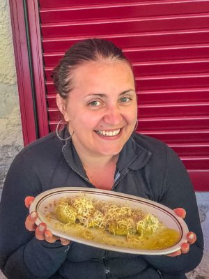 woman holding plate of local italian cuisine at rifugio fonteghi mountain hut in trentino