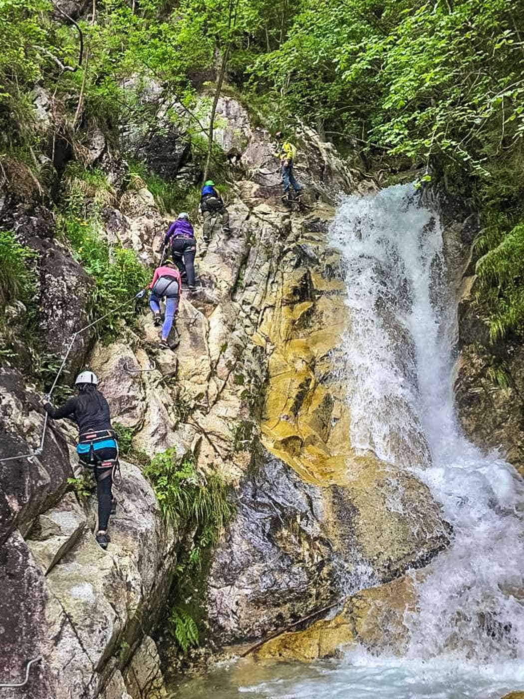 women connected to steel rope near a waterfall