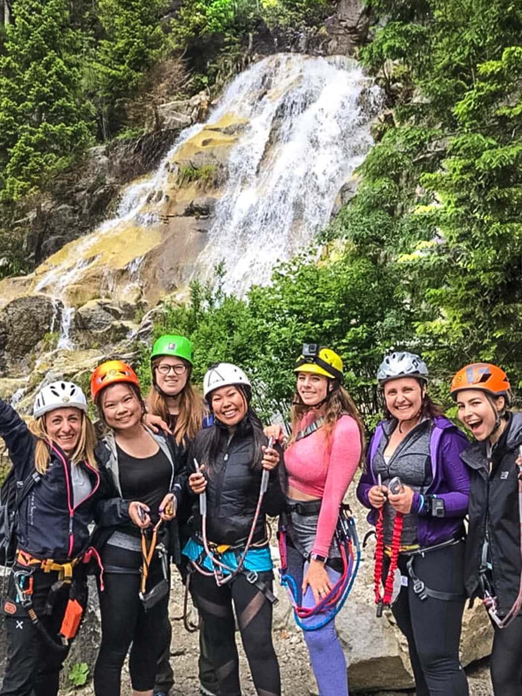 group of women standing in front of a waterfall in trentino