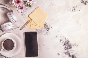 phone laying on a desk next to a coffee and headphones